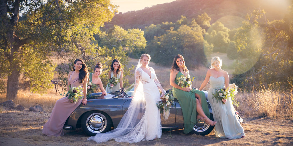 Wedding party posing with vintage car